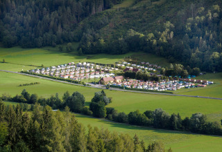 Vista aérea del Camping Bella Austria, un parque vacacional rodeado de campos verdes y bosques en Estiria, Austria.