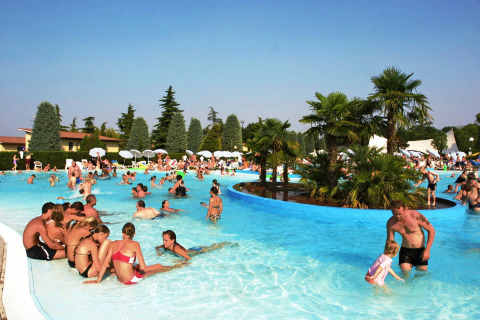 Personas disfrutando junto a la piscina en Camping Bella Italia, un parque vacacional en Véneto, Italia.