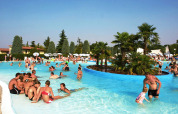 People enjoying a sunny day at the pool in Camping Bella Italia, a holiday park in Veneto, Italy.