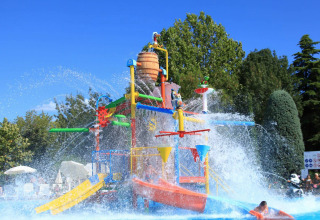 Parco giochi acquatico colorato con scivoli e fontane al Camping Bella Italia, Veneto, Italia.