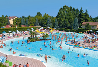 People enjoying a large outdoor pool with water slide at Camping Bella Italia holiday park in Veneto, Italy.