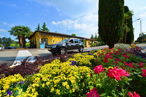 Camas de flores y coche en la entrada de Camping Bella Italia, un parque vacacional en Véneto, Italia.