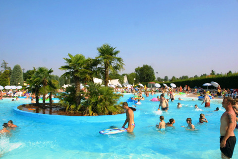 People enjoying a sunny day at the swimming pool of Camping Bella Italia holiday park in Veneto, Italy.
