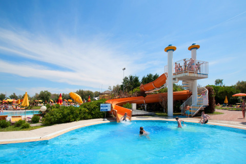 Bambini che giocano in piscina con uno scivolo arancione al Camping Bella Italia, villaggio vacanze in Veneto, Italia.