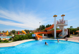 Children playing in the pool with an orange waterslide at Camping Bella Italia holiday park in Veneto, Italy.