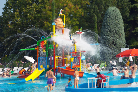 Bambini e famiglie si divertono nel parco acquatico colorato del Camping Bella Italia in Veneto, Italia.