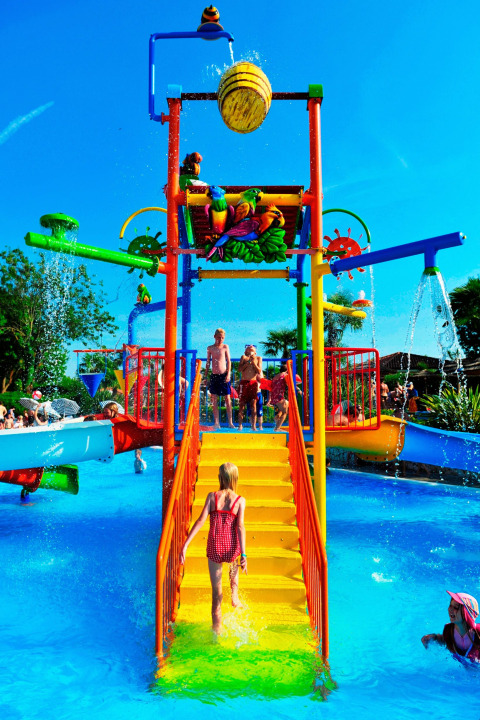 Children playing on a colorful water playground at Camping Bella Italia, Veneto, Italy, on a sunny day.