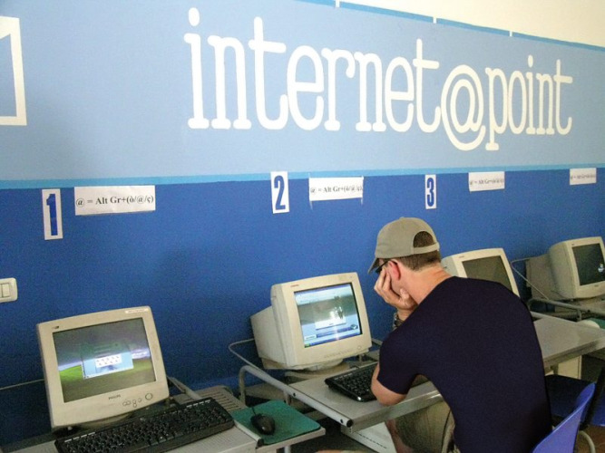 Young man using an old computer at the Internet Point in Camping Bella Italia, Veneto, Italy.