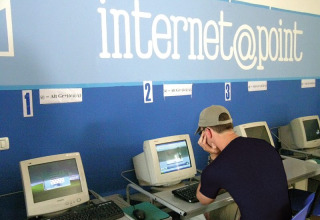 Joven usando un ordenador antiguo en el punto de internet de Camping Bella Italia, Veneto, Italia.