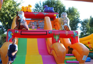 Bambini che giocano su uno scivolo gonfiabile colorato al Camping Bella Italia, villaggio turistico in Veneto, Italia.