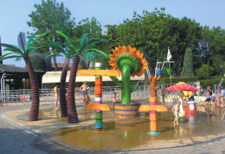 Children play on a colorful splash pad with playful decorations at Camping Bella Italia holiday park in Italy.