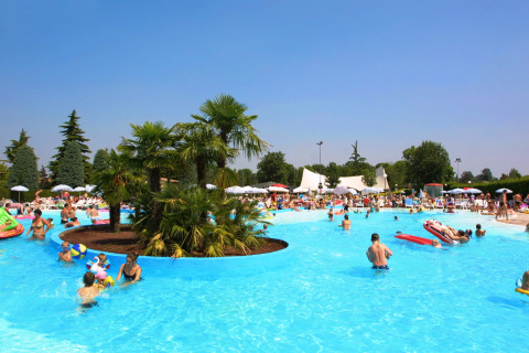 People enjoying a sunny day at the pool in Camping Bella Italia holiday park in Veneto, Italy.