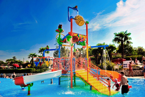 Bambini e adulti giocano in un'area giochi acquatica colorata con scivoli al Camping Bella Italia in Veneto, Italia.