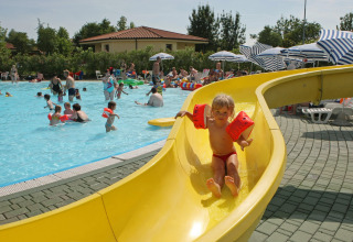 Bambini che giocano in piscina con uno scivolo a Camping Bella Italia, villaggio turistico in Veneto, Italia.