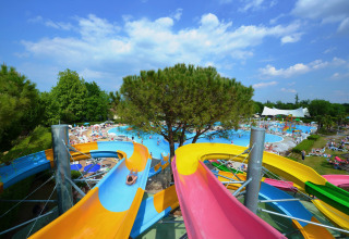 Toboggans aquatiques colorés menant à la piscine principale au Camping Bella Italia, parc de vacances en Vénétie, Italie.