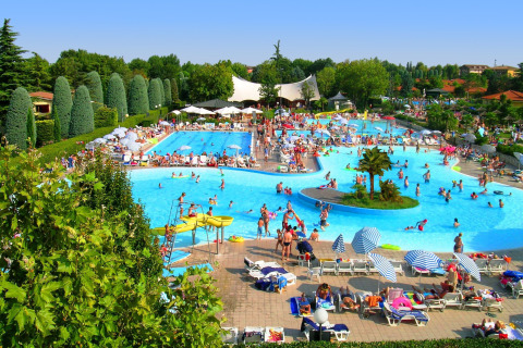 Familias disfrutan de un día soleado en la concurrida piscina de Camping Bella Italia, Veneto, Italia.
