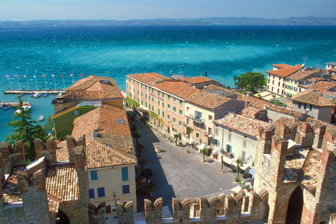 Aerial view of Peschiera del Garda showing colorful rooftops, marina, and vibrant lake in Veneto, Italy.