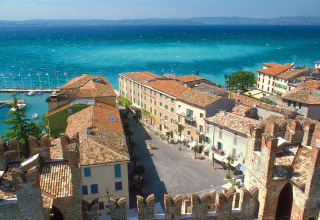 Aerial view of Peschiera del Garda showing colorful rooftops, marina, and vibrant lake in Veneto, Italy.