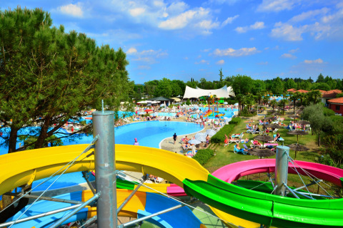 Water park at Camping Bella Italia, Veneto, Italy, with colorful slides and people relaxing in the sun.