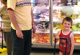 En mand og et barn shopper i en supermarkedsgang med frosne varer i Camping Bella Italia, Veneto, Italien.