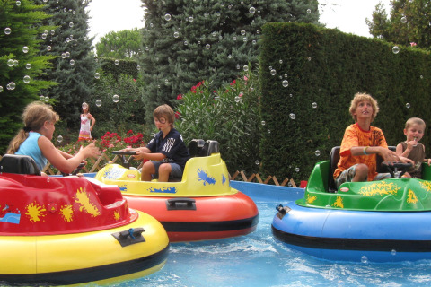 Niños juegan en botes de choque acuáticos en Camping Bella Italia en Veneto, Italia, rodeados de burbujas.