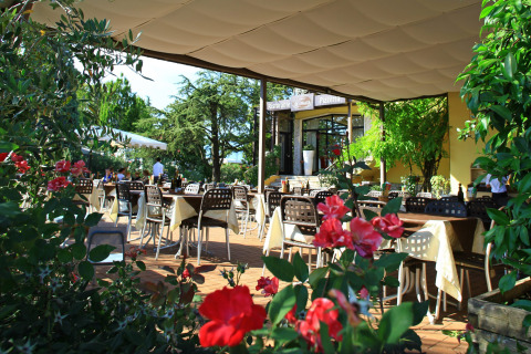 Restaurante al aire libre con mesas y flores en primer plano en Camping Bella Italia en Veneto, Italia.