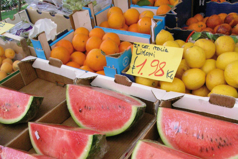 Selezione di frutta fresca, tra cui anguria, arance e limoni, al mercato del Camping Bella Italia, Veneto.
