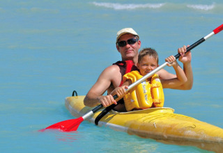 Padre e figlio in kayak sull’acqua azzurra al Camping Bella Italia, villaggio turistico in Veneto, Italia.