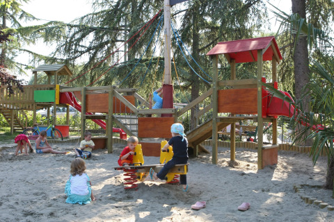 Bambini che giocano nella sabbia con scivoli e strutture da gioco al Camping Bella Italia, Veneto, Italia.