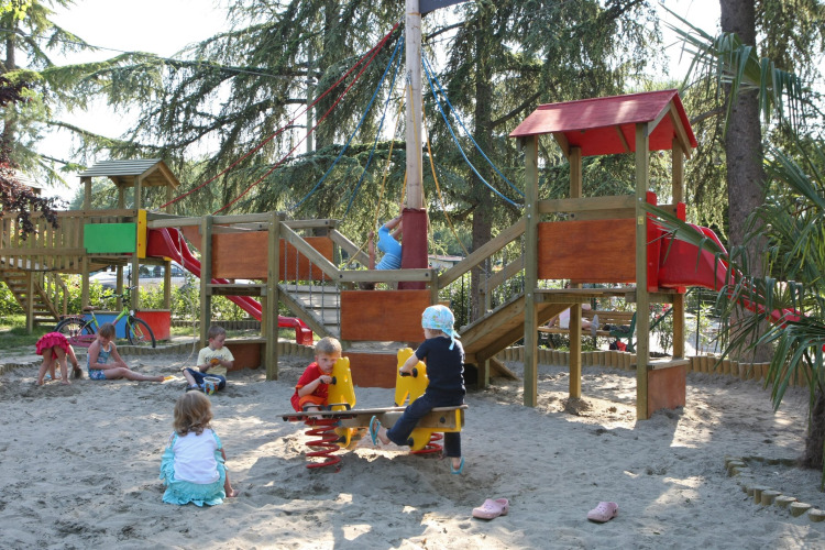 Children playing in the sand with playground equipment and slides at Camping Bella Italia in Veneto, Italy.