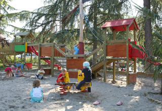 Bambini che giocano nella sabbia con scivoli e strutture da gioco al Camping Bella Italia, Veneto, Italia.