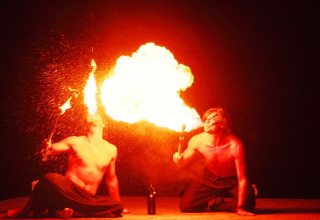 Two performers do a fire-breathing show at Camping Bella Italia, Veneto, Italy, with bright flames at night.