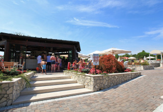 Ospiti si rilassano al bar all’aperto del Camping Bella Italia, parco vacanze in Veneto, Italia.