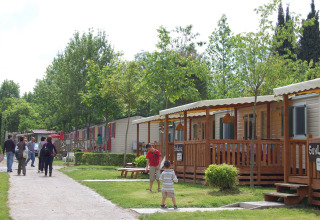 Familier og børn nyder deres ophold blandt mobilhomes på Camping Bella Italia feriepark i Veneto, Italien.