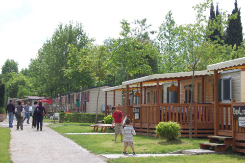Familier og børn nyder deres ophold blandt mobilhomes på Camping Bella Italia feriepark i Veneto, Italien.