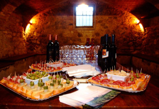 Vinflasker, glas og italienske appetitvækkere på et rustikt bord i Camping Bella Italia, Veneto, Italien.