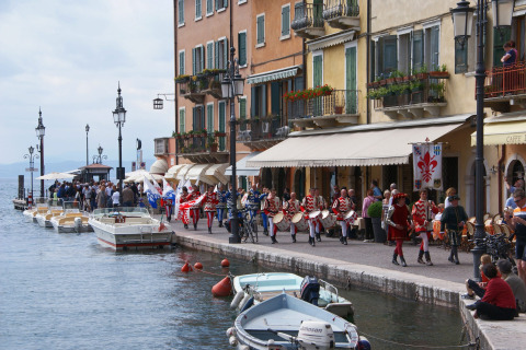 Parade along the waterfront with boats and colorful buildings at Camping Bella Italia, Veneto, Italy.