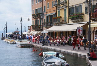 Parade ved søpromenade med både og farverige bygninger ved Camping Bella Italia, Veneto, Italien.