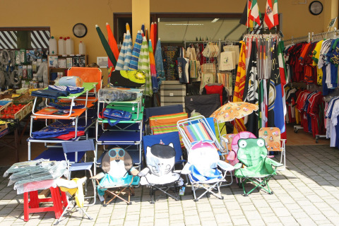 Negozio presso Camping Bella Italia in Veneto, Italia, con sedie da spiaggia, ombrelloni e abbigliamento.
