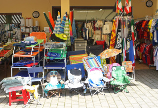 Butik ved Camping Bella Italia i Veneto, Italien, med strandstole, parasoller, tøj og campingudstyr.