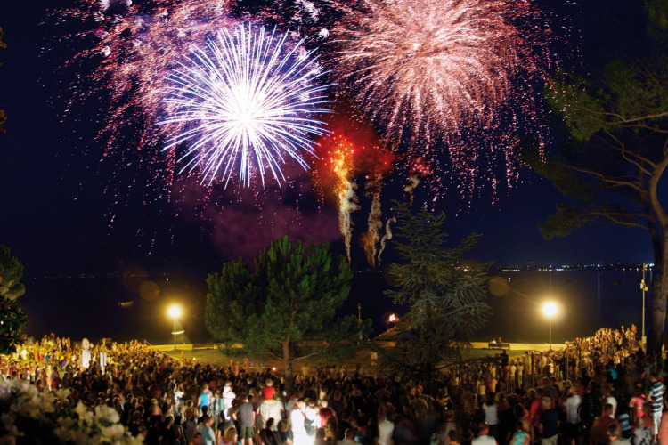 Colorful fireworks light up the night sky above a large crowd at Camping Bella Italia in Veneto, Italy.