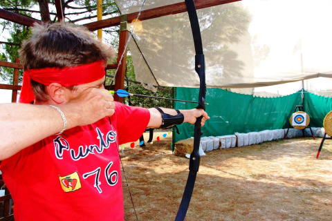 Persona con cinta roja dispara un arco en un campo de tiro en Camping Bella Italia, Véneto, Italia.