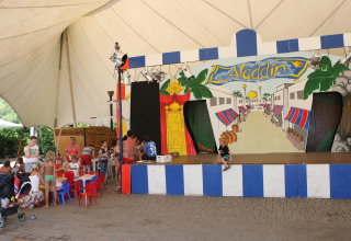 Bambini e famiglie partecipano ad attività vicino al palco di Aladdin al Camping Bella Italia in Veneto.