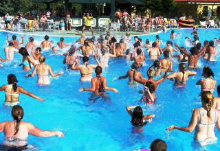 En stor gruppe mennesker deltager i vandaerobic i en udendørs swimmingpool på Camping Bella Italia i Italien.