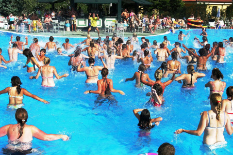 Een grote groep mensen doet mee aan aquagym in het buitenzwembad van Camping Bella Italia in Veneto, Italië.