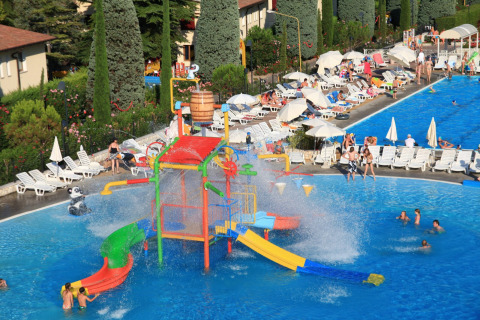 View of Camping Bella Italia in Veneto, Italy showing colorful water playground, pool, and relaxing holidaymakers.