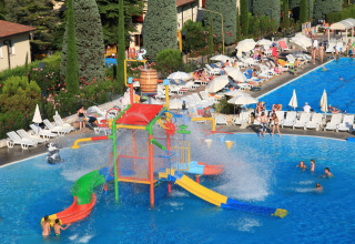 View of Camping Bella Italia in Veneto, Italy showing colorful water playground, pool, and relaxing holidaymakers.