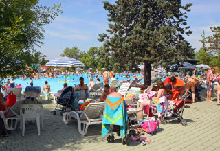 Familias descansando junto a la piscina concurrida en Camping Bella Italia, parque vacacional en Véneto, Italia.