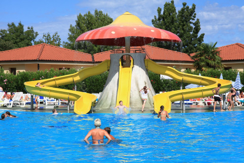 Niños y adultos disfrutan de los toboganes acuáticos en la piscina de Camping Bella Italia, Veneto, Italia.