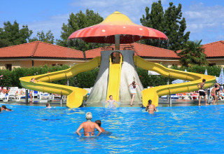 Children and adults enjoy waterslides at a swimming pool in Camping Bella Italia holiday park, Veneto, Italy.
